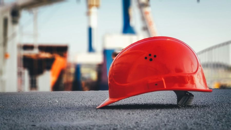 Ein roter Helm liegt auf einer gemauerten Wand auf der Baustelle.