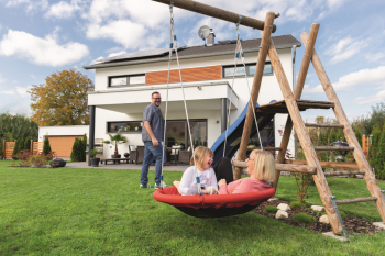Familie im Garten vorm Neubauhaus
