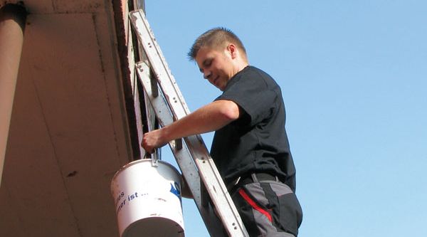 Mann steht auf Leiter, die an den Balkon gelehnt ist