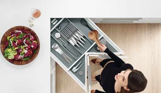 Frau öffnet Besteckschublade in Eckschrank