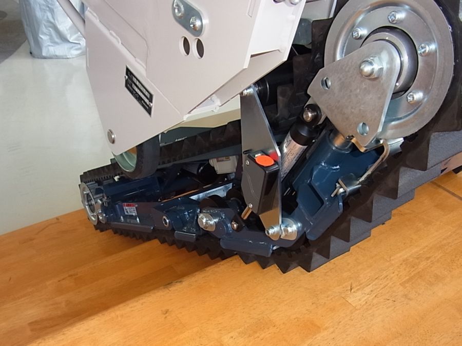 Detailansicht einer Treppenraupe auf einer Holztreppe, Fokus auf Kettenantrieb und Mechanik.