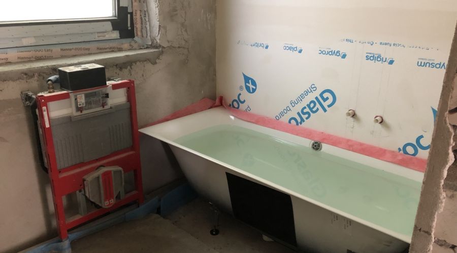 Badezimmer im Rohbauzustand mit gefüllter Badewanne