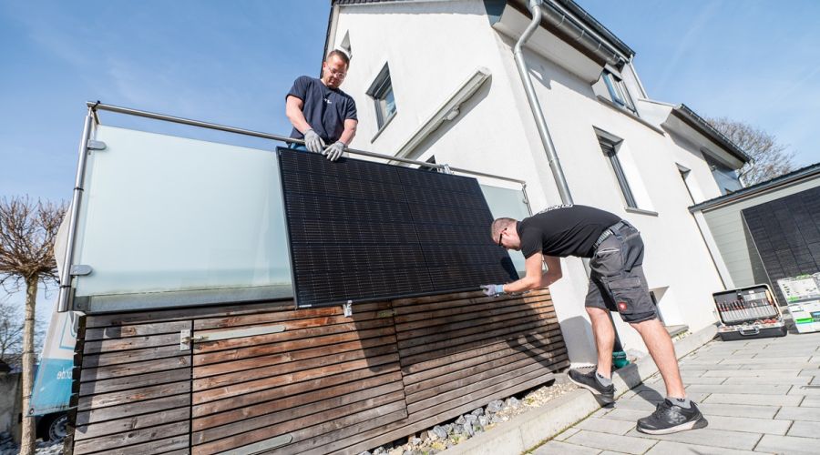 Zwei Männer montieren eine Solaranlage am Balkon