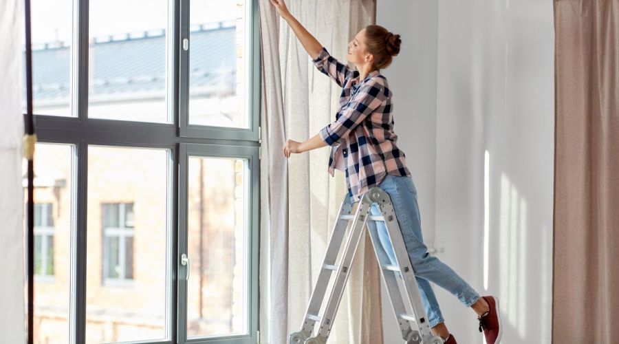 Frau dekoriert Fenster mit Gardine