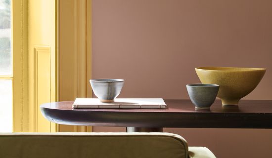 Stilleben mit rosa Wand, gelbem Türrahmen und gelben Dekoobjekten