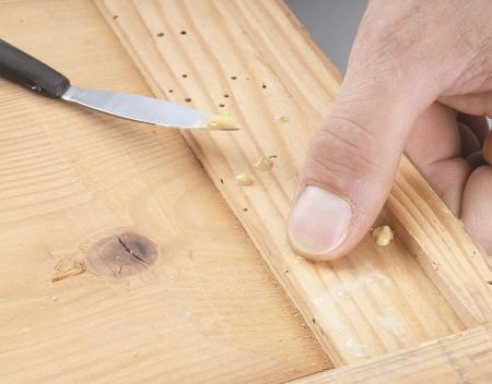 Holzwurmlöcher werden mit Holzkitt verschlossen