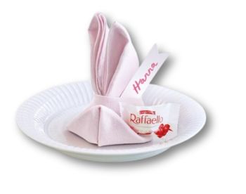 Einzelner rosafarbener Osterhase auf einem Teller, aus einer Serviette gefaltet