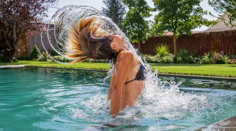 Frau taucht aus Wasser im Schwimmteich auf