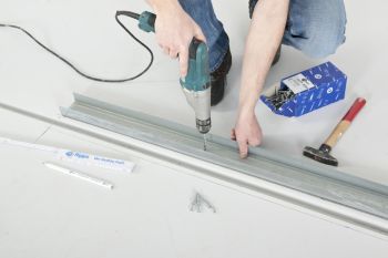 Mann bohrt Löcher in Bodenschiene