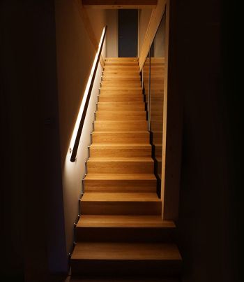 Offene Holztreppe mit indirekter Beleuchtung entlang der Treppenstufen