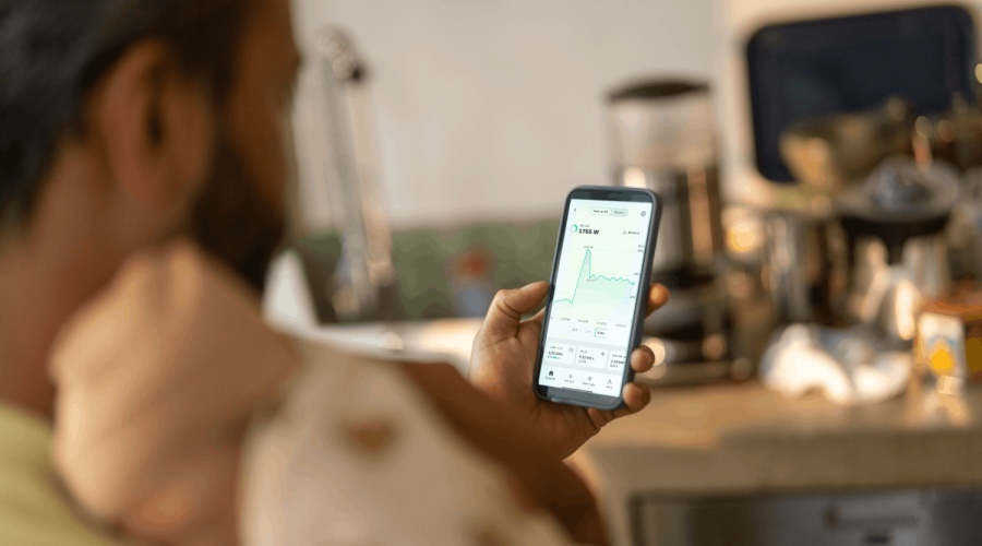 Mann sitzt im Sessel und checkt seinen Stromverbrauch am Smartphone